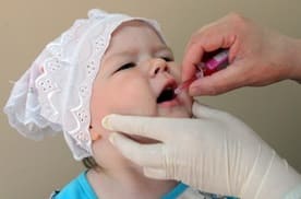 Ребенок орально принимает жидкую вакцину